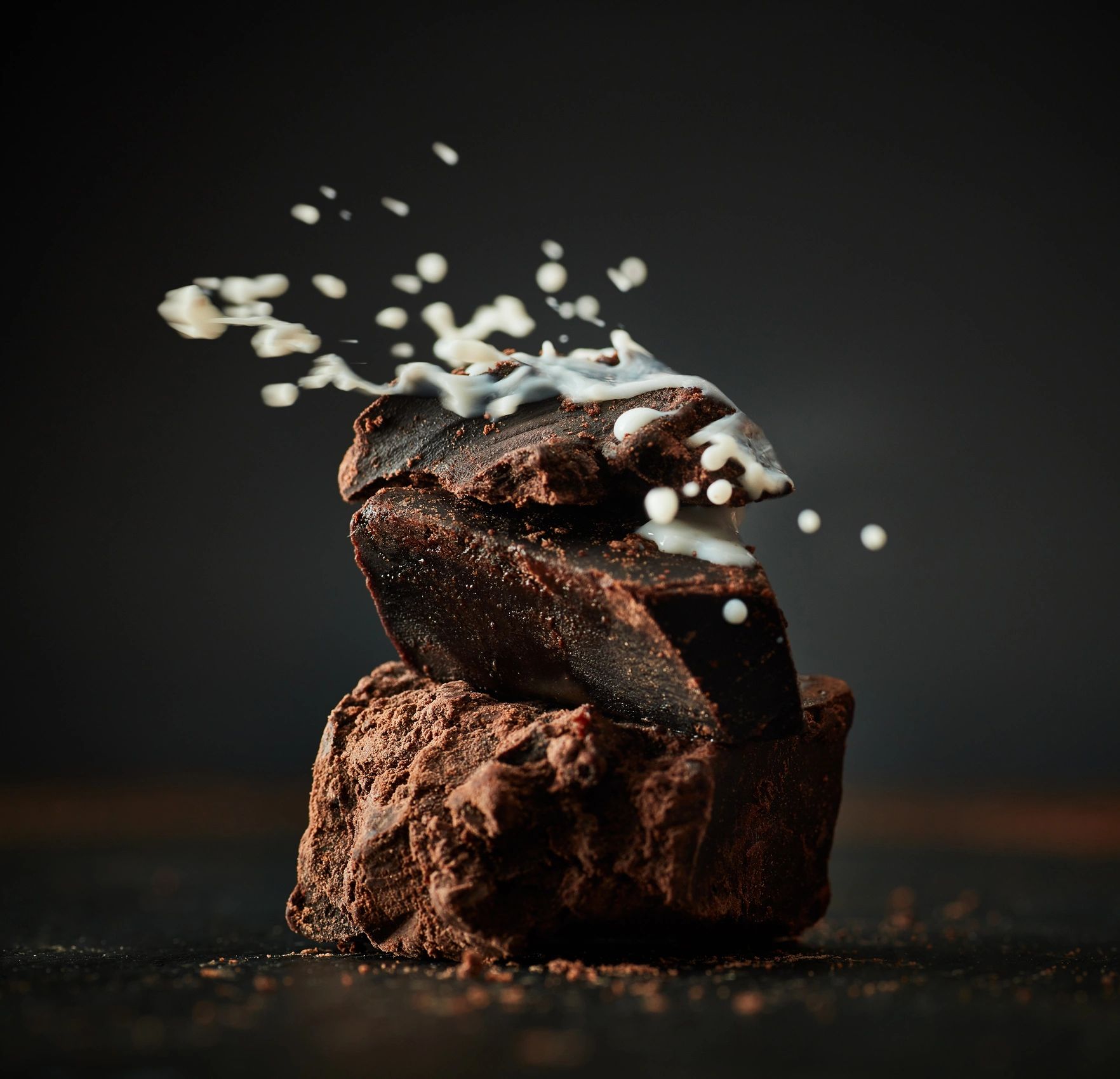 Milch-Splash auf dunkler Schokolade als stimmungsvolles Detailbild